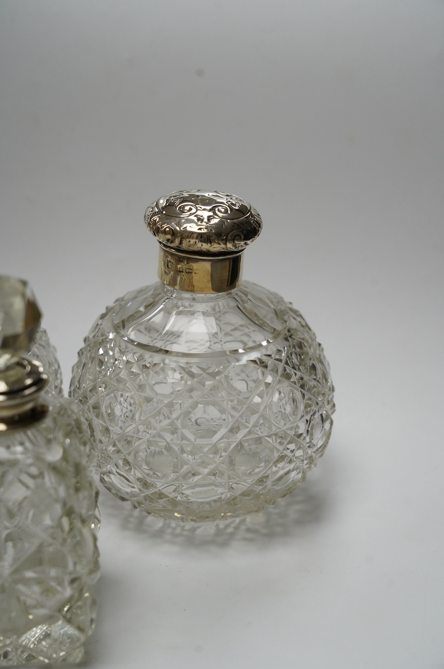 A pair of silver mounted cut glass scent bottles, marks rubbed, 12.3cm and one other silver mounted scent bottle. Condition - poor